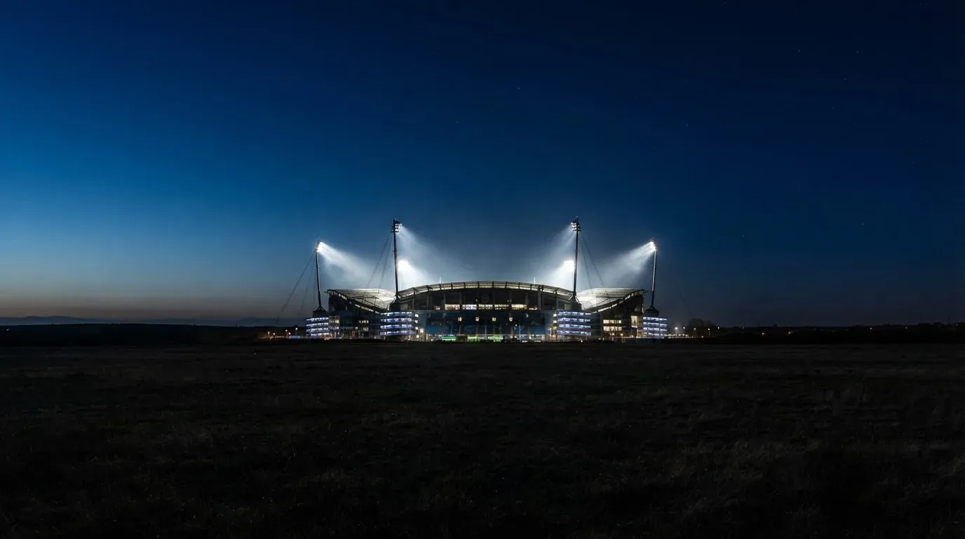 Ein Stadion unter Flutlicht aus großer Entfernung gesehen, der Himmel darüber ist tiefblau.