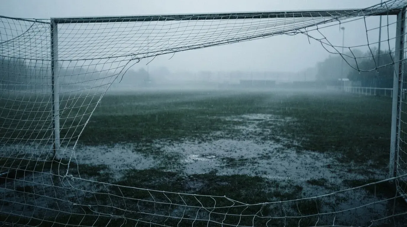 Ein Fußballtor mit Netz auf einem Trainingsplatz bei Regen, Pfützen stehen auf dem Rasen, niemand ist zu sehen.