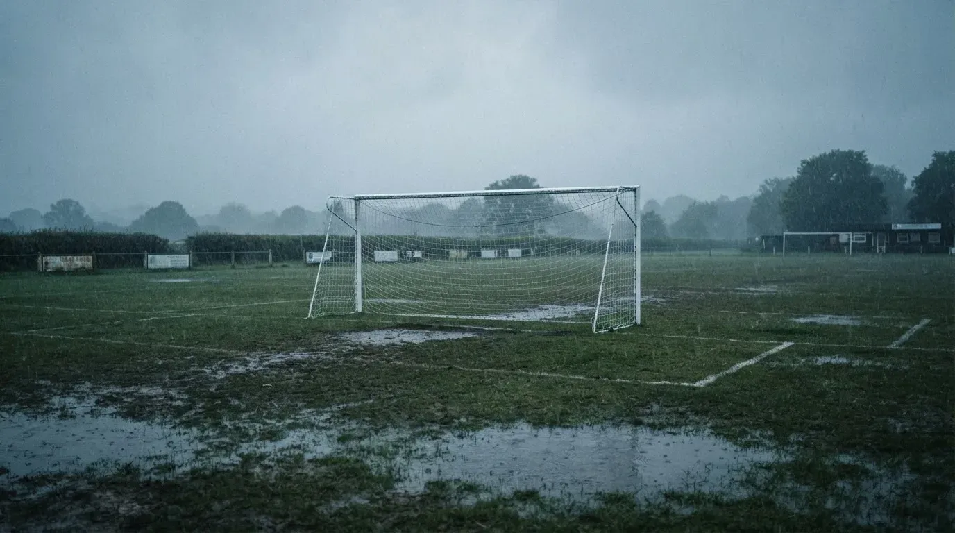 Ein Fußballtor mit Netz auf einem Trainingsplatz bei Regen, Pfützen stehen auf dem Rasen, niemand ist zu sehen.